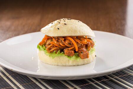 Bbq pork vietnamese bao burger with pepper on white plate on wooden table side viewの写真素材