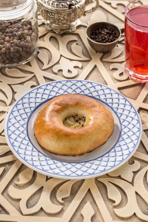Fresh baked pasty with sesame seeds and glass of red drink on oriental wooden table side viewの写真素材