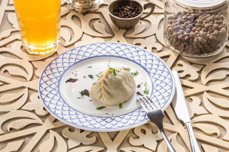 Dumpling with Butter on white plate and glass of yellow drink on oriental wooden table side viewの写真素材