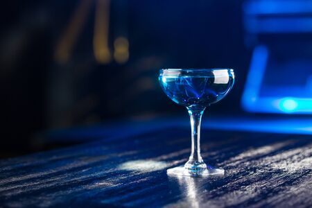 Blue margarita cocktail on the table on club bar background side view