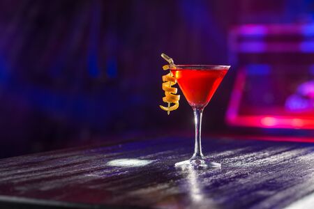 Red cosmopolitan cocktail with orange peel on the table on nightclub background side viewの写真素材