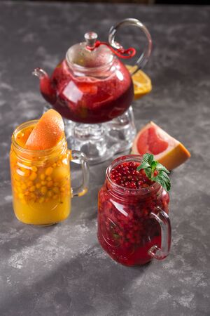 Two mason jars with hot organic sea buckthorn tea and cranberry mint tea on grey background side viewの写真素材