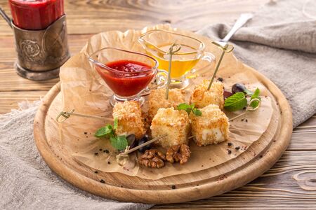deep fried camembert cheese cubes with cranberry sauce and honey on wooden table side viewの写真素材