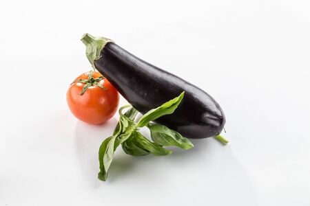 raw uncooked tomato, aubergine and basil leaves on white background with shadow side viewの写真素材