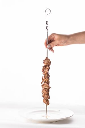 female hand holding shish kebab on metal skewer isolated on white background side viewの写真素材