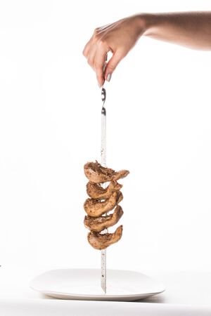 female hand holding skewer with grilled lamb tongue isolated on white background side viewの写真素材