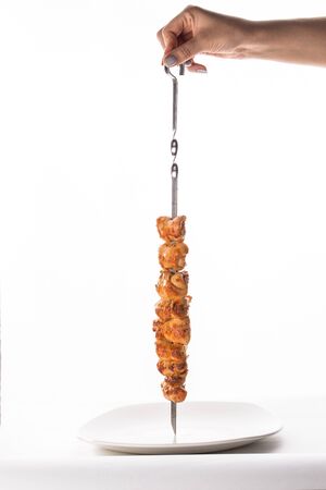 female hand holding skewer with grilled chicken isolated on white background side viewの写真素材