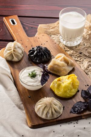 variety of dumplings manti and khinkali with sour cream on wooden board on wooden table side viewの写真素材