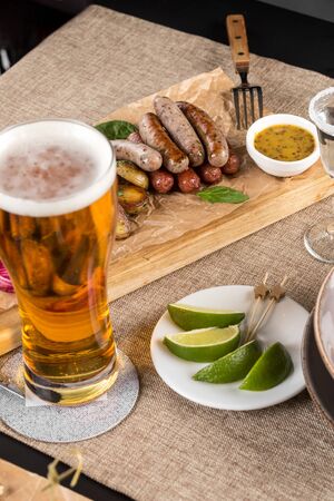 weisswurst grilled sausages served with baked potato and mustard for Octoberfest with glass of beer at restaurant side viewの写真素材