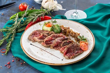 slices of roast beef with pickled onion with glass of red wine on blue background side viewの写真素材