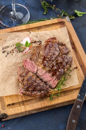 Grilled Ribeye Steak with knife on wooden board on blue background side viewの写真素材