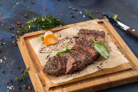 Grilled Ribeye Steak with knife on wooden board on blue background side viewの写真素材