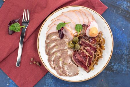meat delicatessen snack plate with roast beef, ham and boiled pork on red blue background top viewの写真素材