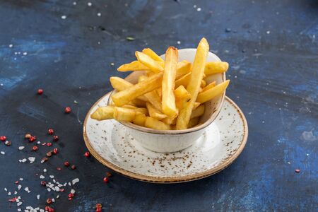 French fries in white bowl isolated on blue background side viewの写真素材