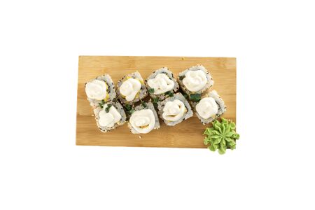 Sushi maki rolls with sesame seeds and mayonnaise on top on wooden board isolated on white background top viewの写真素材