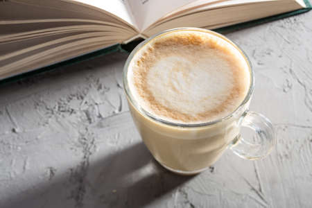 transparent cup of coffee with Latte art on concrete table with book side viewの写真素材