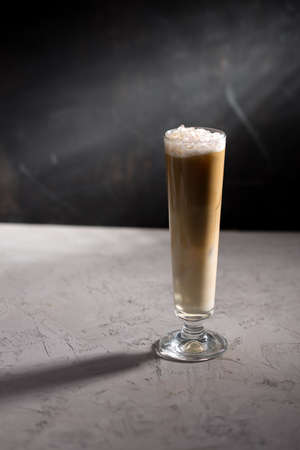 Summer iced coffee  frappe or latte in tall glass on concrete table on black background side viewの写真素材