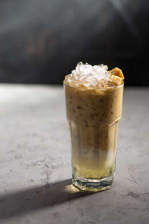 Iced coffee with vanilla syrup and milk on concrete table on black background side viewの写真素材