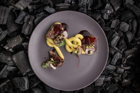 braised beef meat with mashed potato snack on charcoal black background top viewの写真素材