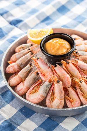 steamed large shrimp with cheese sauce and lemon on plate on fabric napkin background side viewの写真素材