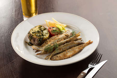 Seafood deep fried fish served with baked potato and beer on wooden table side viewの写真素材