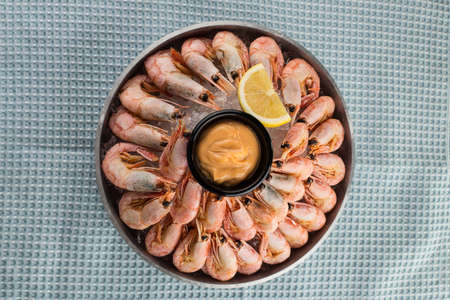 steamed large shrimp with cheese sauce and lemon on plate on fabric napkin background top viewの写真素材