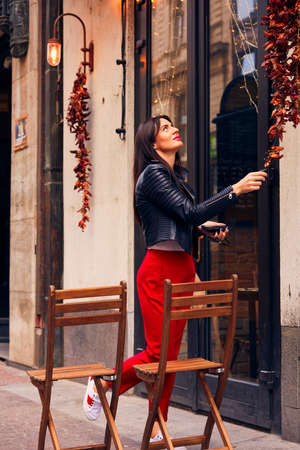 Beautiful stylish brunette girl posing near cafe with lights on the streetの写真素材