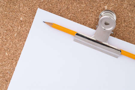 White Paper, Paperclip and Pencil over cork surfaceの写真素材