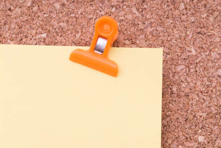 Yellow Note Paper With Paperclip On Cork Surfaceの写真素材