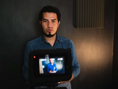 Young man recording a video in a studio with camera.