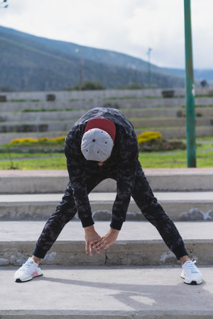 Young man doing different warm-up and cardio exercises in the park.の写真素材
