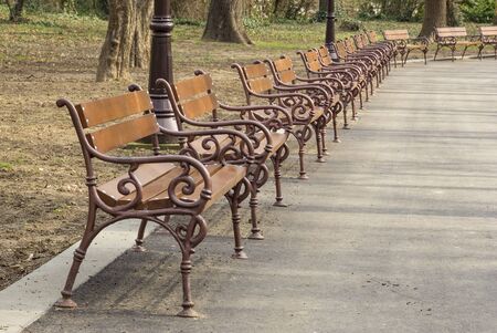 Empty wooden park benches with metal railingの写真素材