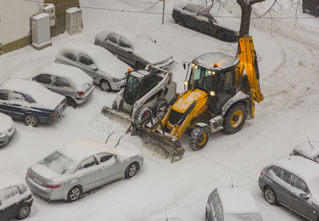 two excavators cleaning snow on car parking. Top view.