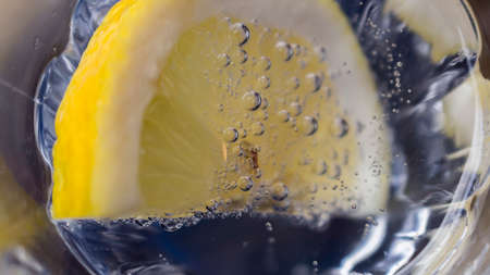 a slice of lemon dipped in sparkling water. close up