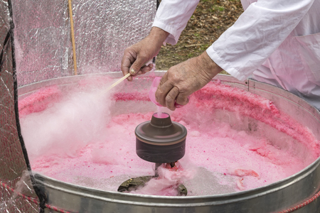 Hand rolling cotton candy in candy floss machine. Making candyfloss.の写真素材
