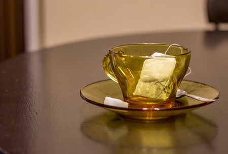 Empty cup with tea bag, spoon and sugar on tableの写真素材