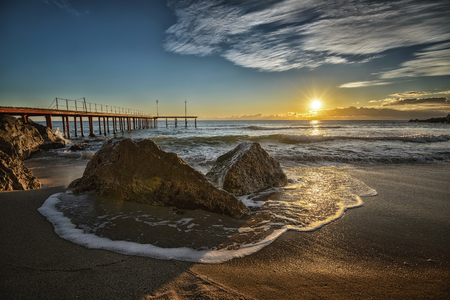 Sunrise over the sea with long exposure wave around rocks.の写真素材