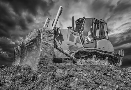 Amazing black and white view of stopped bulldozer and blade into the ground. Wide angle, close upの写真素材