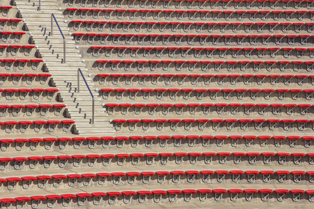 Empty red plastic chairs in the stands of the stadium or amphitheater. Many empty seats for...