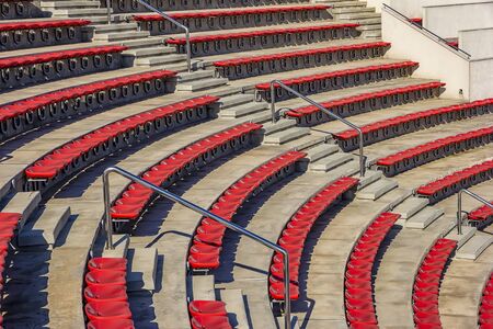 Empty red plastic chairs in the stands of the stadium or amphitheater. Many empty seats for spectators in the stands.の写真素材