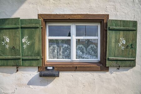 Old ancient wooden window with blinds, curtains and mailbox. Scenic original and colorful view of antique windows in the old city in Germany. No people. Front view. Old fashioned style.の写真素材