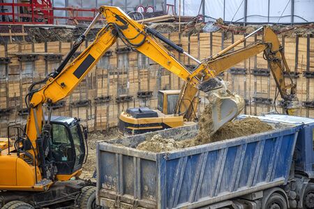Excavator is loading excavation on the truck. Heavy construction equipment working at the construction site.の写真素材