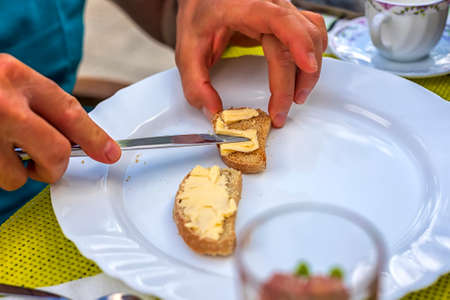 Morning, man preparead slice of bread with butterの写真素材