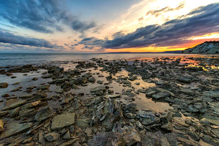 Stone beach at sunset. Twilight sea and sky. Dramatic sky and clouds. Nature landscape.の写真素材