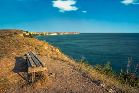 empty bench on the top of sea rocks with a vast view for relaxationの写真素材