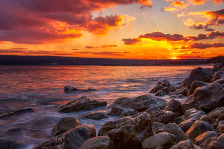 Sunning long exposure sunset over the sea with a rocky beachの写真素材