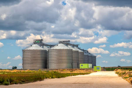 Landscape with modern agricultural Silo. Set of storage tanks cultivated agricultural crops processing plant.の写真素材
