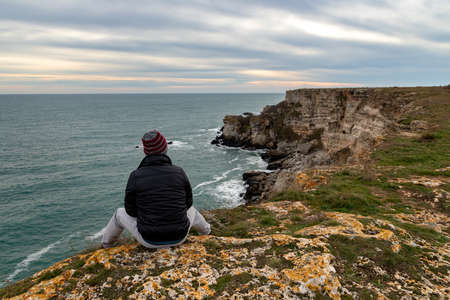 A man enjoys a beautiful sea view from the top of a cliff.の写真素材