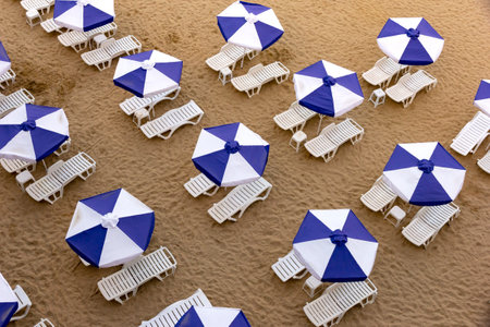 Aerial top view of a beach with white umbrellas and blue lounge chairsの写真素材