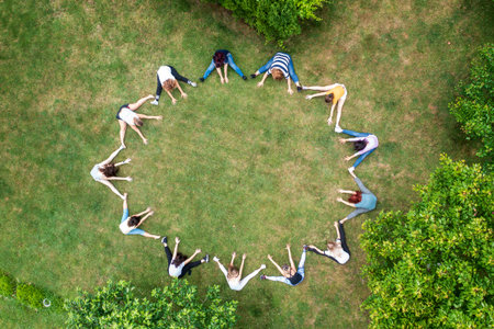 Top view of people standing in circle on green grass doing exercisesの写真素材